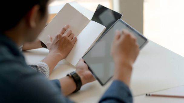 Cropped shot of two businesspeople consulting on their work with mock up tablet and notebook on white desk - Fotoğraf, Görsel