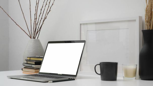 Обрезанный снимок минимального рабочего пространства с чистым экраном ноутбука, офисных принадлежностей и украшений на белом столе с белым фоном стены
 - Фото, изображение