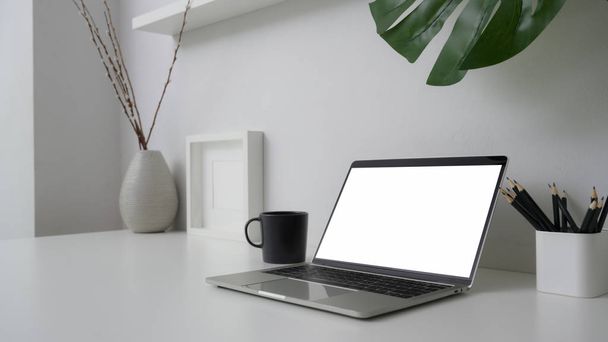 Cropped shot of trendy workspace with blank screen laptop, stationery and decorations on white desk with white wall background - Fotografie, Obrázek