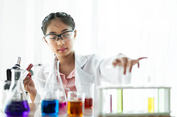 Teini-ikäiset tytöt opiskelijat oppivat ja tekevät kemiallisen kokeen ja pitävät koeputkea käsissä tieteen luokassa pöydällä.Koulutuskonsepti
 - Valokuva, kuva