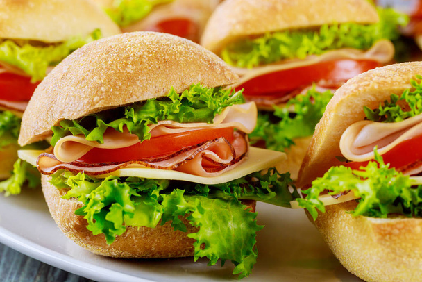 Deliciosos sándwiches hechos de rollo de ciabatta con jamón, queso, lechuga y tomate. De cerca.
. - Foto, Imagen