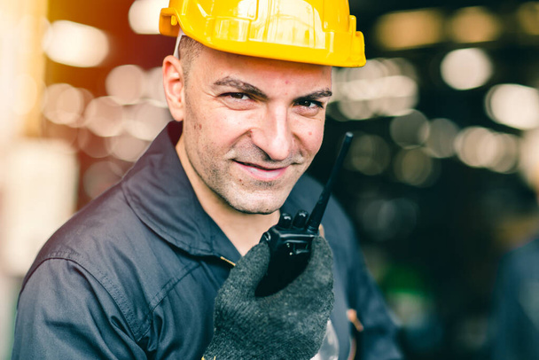 Retrato de mano de ingeniero obrero sosteniendo la radio para hablar de comunicación con el compañero de trabajo en la fábrica industrial y el traje de seguridad de almacenamiento
. - Foto, imagen