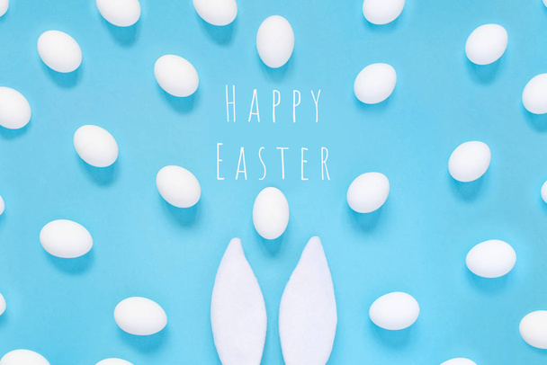 Easter concept. Rabbit ears and white eggs. On a blue background. - Valokuva, kuva