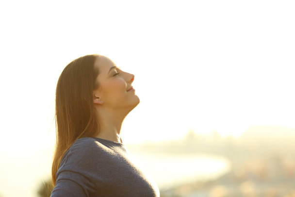 Side view portrait of a single woman breathing deeply fresh air at sunset - Foto, imagen