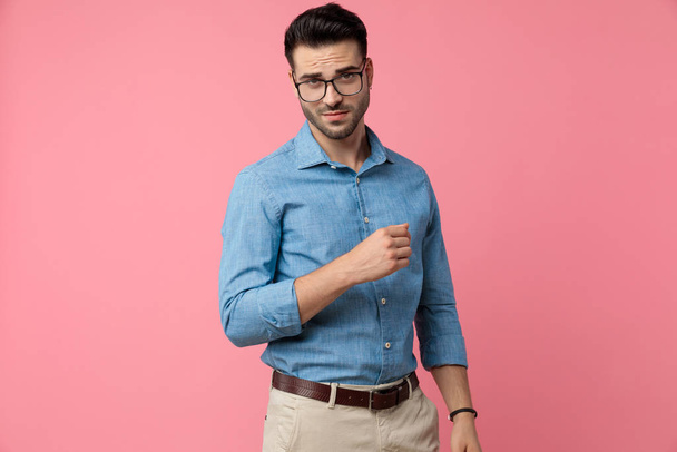 young fashion model wearing glasses and holding hands in a fashion pose on pink background - Photo, Image