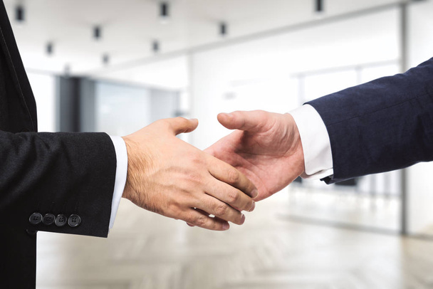 Dois empresários apertam as mãos no fundo do moderno escritório mobiliado, conceito de negócio, close-up
 - Foto, Imagem