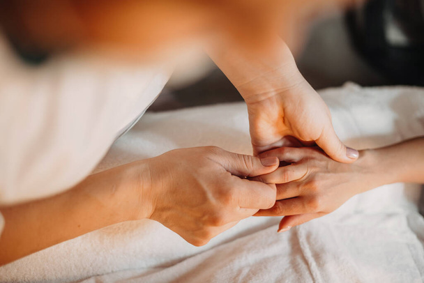 Médico caucasiano atento e concentrado está massageando cuidadosamente clientes dedos segurando sua palma pequena
 - Foto, Imagem