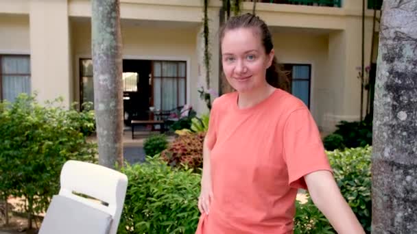 Mosolygó nő áll a szálloda udvarán - Felvétel, videó
