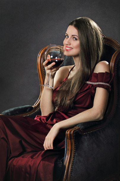 Smiling attractive woman poses with a glass of red wine - Foto, afbeelding