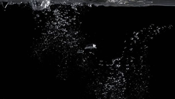 Burbujas bajo el agua salpicaduras y flotando y fondo de color negro que representan bebidas carbonatadas como refrescos o cola y agua con gas de la naturaleza que puede utilizar para el concepto refrescante o refrescante
 - Foto, Imagen