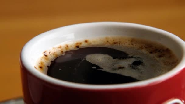 Red cup with hot black coffee rotating, close up macro - Кадри, відео