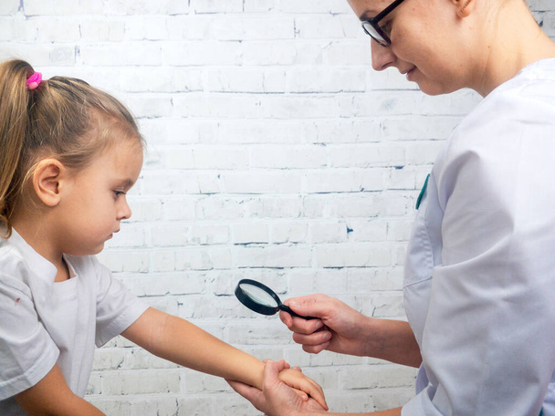 Dermatolog sprawdzi rękę dziewczynki w szafce. - Zdjęcie, obraz