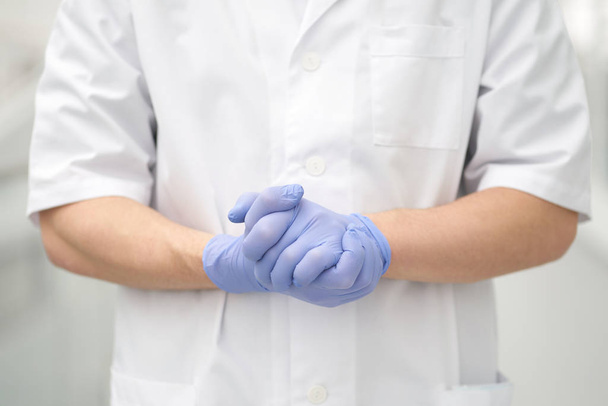 Handen van de arts gedragen in medische handschoenen in zelfverzekerd gebaar - Foto, afbeelding