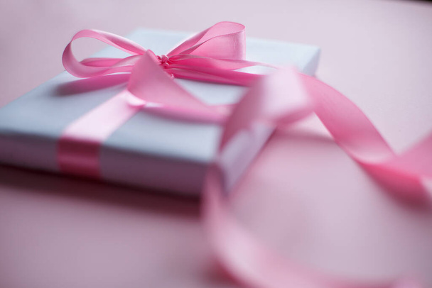 Dekoratív fehér ajándék doboz rózsaszín íj és hosszú szép szalag rózsaszín háttér - Fotó, kép