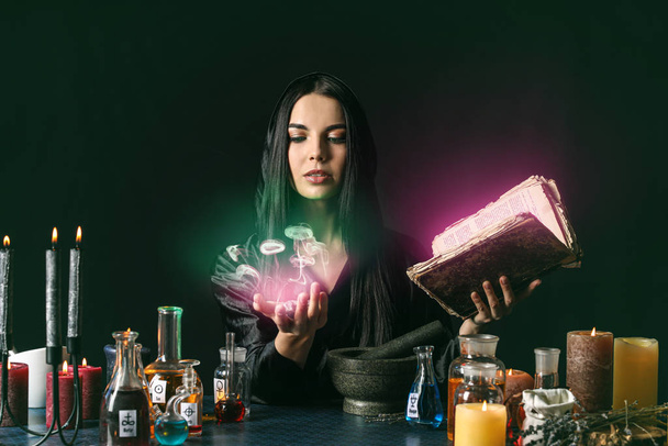 Alchimiste féminine faisant de la potion sur fond sombre - Photo, image