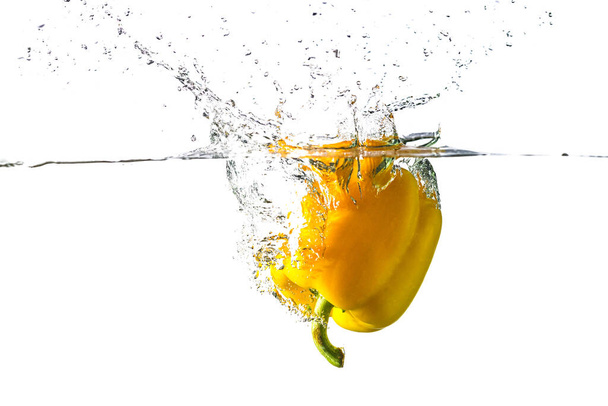 Gele paprika met spray geïsoleerd op wit. Verse groenten voor salade. - Foto, afbeelding