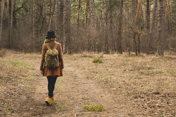 Happy woman hiking outdoors with bag and hat, cold outerwear gear.Adventure, tourism, hike, travel and people concept. Hipster young girl with backpack enjoying wild journey. Backpack and boots.  - Photo, Image
