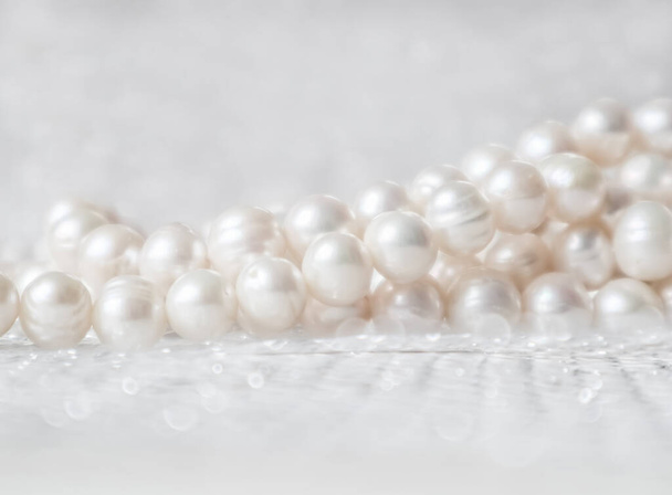 Природа білої нитки перлів на блискучому фоні в м'якому фокусі, з підсвічуванням
 - Фото, зображення
