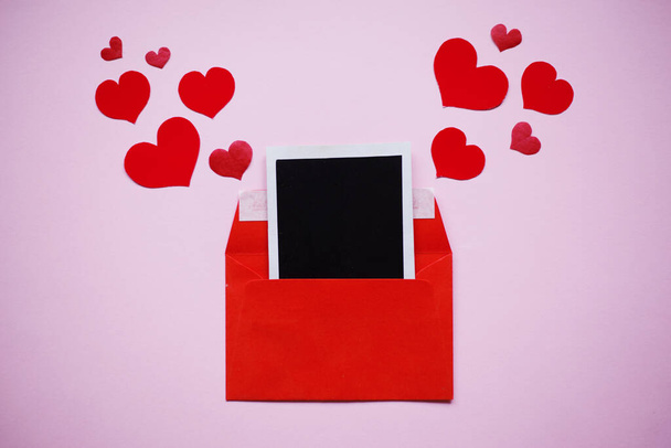Kırmızı zarf ve pembe zemin üzerinde siyah kare kağıt olan kırmızı kalpler, sevgililer günü konsepti - Fotoğraf, Görsel