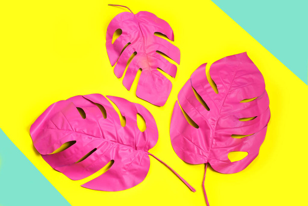 Três folhas de palmeira tropical rosa de monstera em fundo amarelo. conceito rosa moda. minimalismo. Conceito de verão. Arte conceitual. Deitado plano, vista superior
 - Foto, Imagem