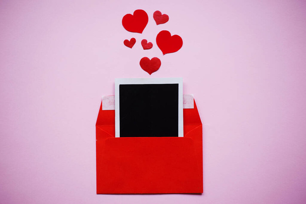 Czerwona koperta i serca z czarnym pustym kwadratowym papierem na różowym tle, koncepcja Walentynki - Zdjęcie, obraz