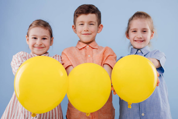 three happy kids girl and boy with yellow balloon with smile. - Φωτογραφία, εικόνα