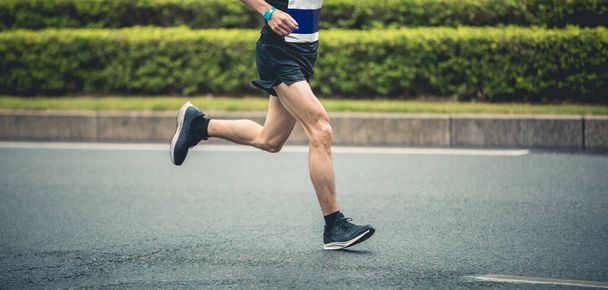 Обрізаний бігун чоловічого марафону біжить на гонці по міській дорозі
 - Фото, зображення