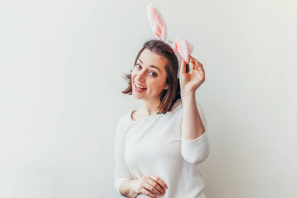 Feliz Pascua celebración primavera concepto. Mujer joven con orejas de conejo aisladas sobre fondo blanco. Preparación para las vacaciones. Chica buscando feliz y emocionado, divertirse en el día de Pascua - Foto, Imagen