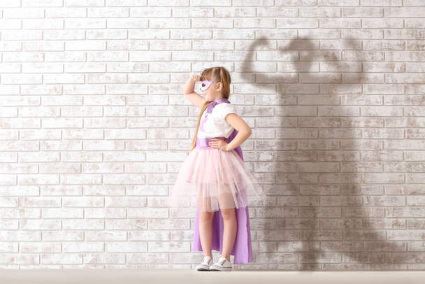 Linda niña vestida como superhéroe cerca de la pared de ladrillo
 - Foto, imagen