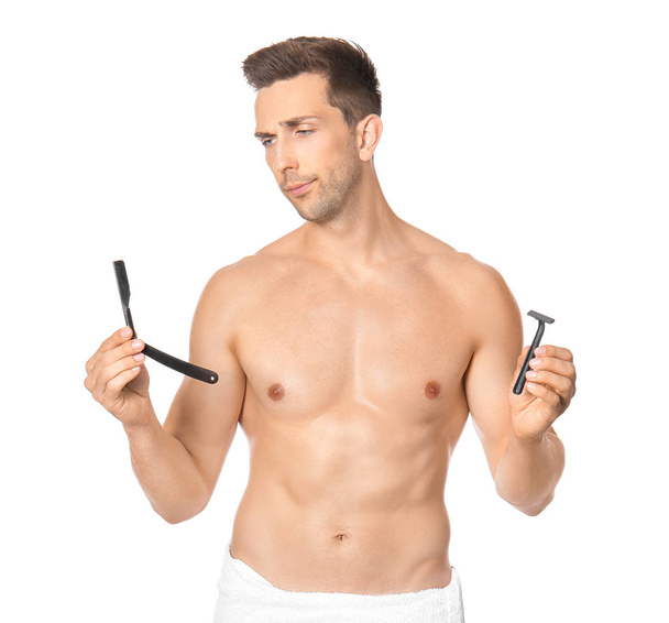 Handsome young man with different razors on white background - Photo, Image