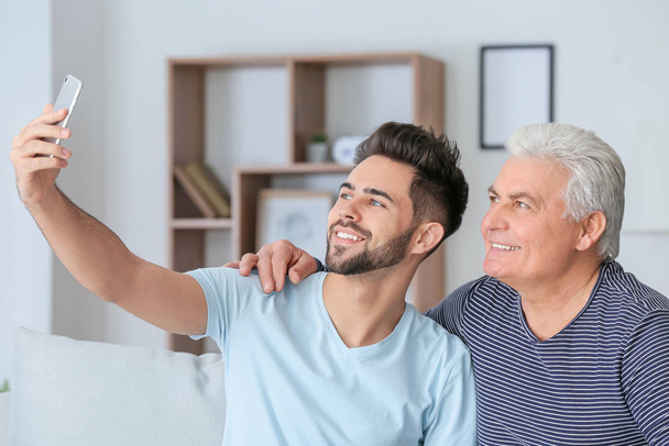 Young man and his father taking selfie at home - Foto, Bild