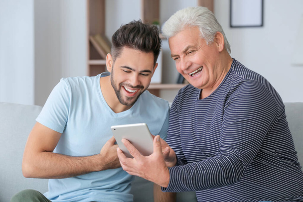 Jovem e seu pai com computador tablet em casa
 - Foto, Imagem