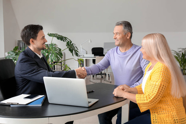 Male real estate agent working with mature couple in office - Photo, Image