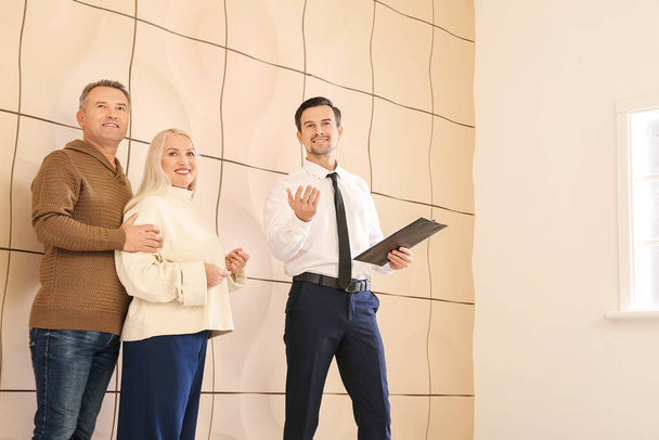 Male real estate agent showing mature couple a new house - Photo, image