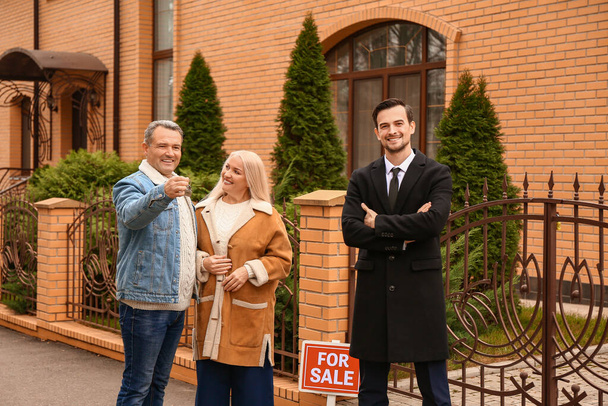 Homme agent immobilier et couple d'âge mûr avec clé de leur nouvelle maison à l'extérieur
 - Photo, image