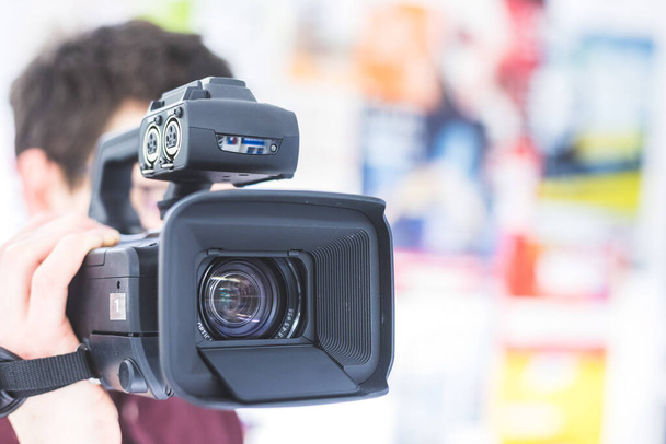 Männlicher Kameramann hält einen professionellen Video-Camcorder, verschwommener Hintergrund - Foto, Bild