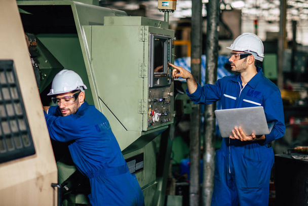 Команда технического обслуживания станков проверяет ЧПУ и процесс перепрограммирования во время производства на заводе
. - Фото, изображение