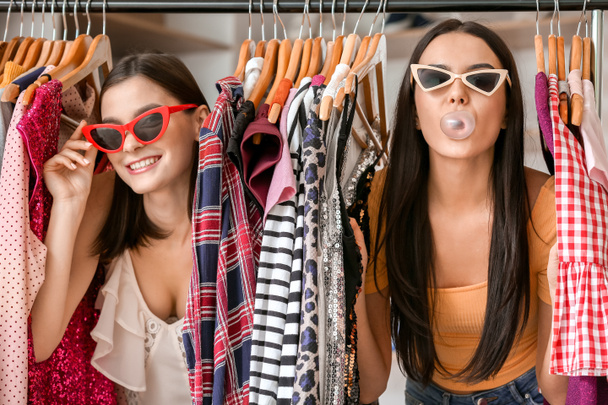 Mujeres jóvenes eligiendo ropa en la tienda moderna
 - Foto, imagen