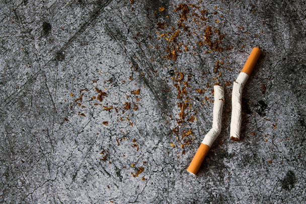 Two broken cigarettes with spilled tobacco on a gray textural background with space for copying. The concept of a healthy lifestyle, Smoking cessation - Foto, afbeelding
