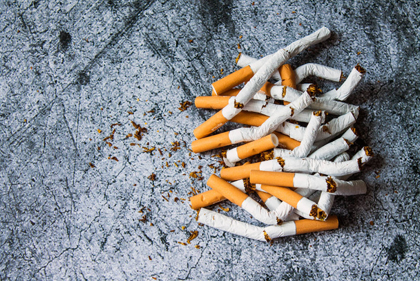 A pile of broken cigarettes on a gray textural background. The concept of a healthy lifestyle, quitting Smoking - Foto, Imagen