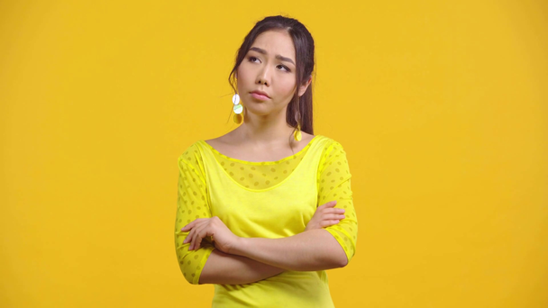 unzufriedene asiatische Frau mit verschränkten Armen auf gelb isoliert  - Filmmaterial, Video