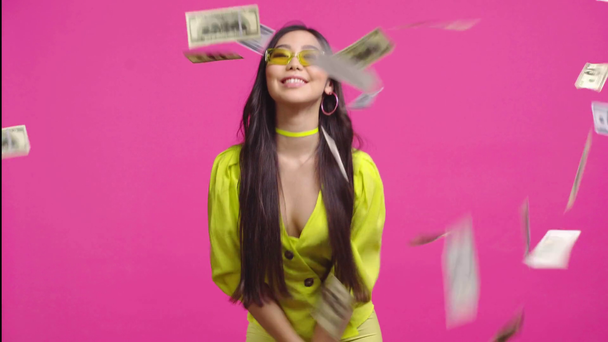 Azji dziewczyna rzucając w powietrze pieniądze izolowane na różowy  - Materiał filmowy, wideo