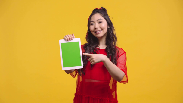 ázsiai lány gazdaság digitális tabletta zöld képernyő elszigetelt sárga  - Felvétel, videó