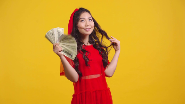 happy asian girl waving money isolated on yellow  - Footage, Video