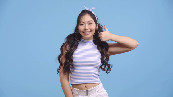 feliz asiático chica mostrando pulgar arriba aislado en azul
  - Imágenes, Vídeo