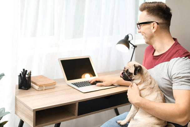 Hezký muž s roztomilým psíkem a notebookem doma - Fotografie, Obrázek