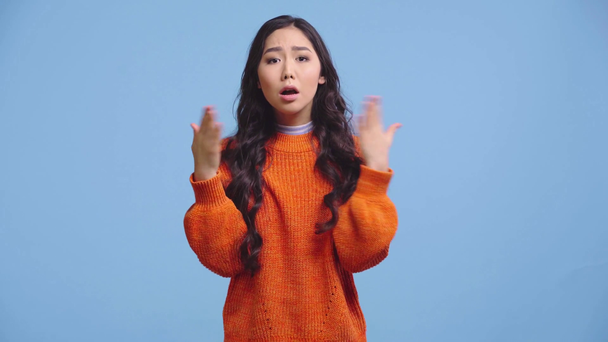bonita chica kazakh en suéter sensación caliente aislado en azul
 - Imágenes, Vídeo