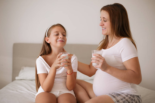 Pregnant mother with daughter drinks milk - 写真・画像