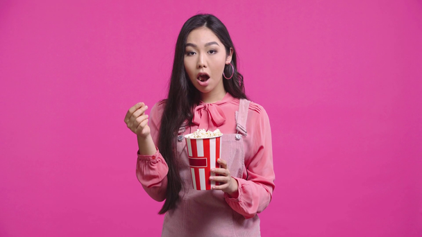 gyönyörű kazah lány eszik popcorn elszigetelt rózsaszín  - Felvétel, videó