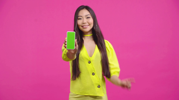 niña kazakh sosteniendo teléfono inteligente con pantalla verde aislado en rosa
  - Metraje, vídeo